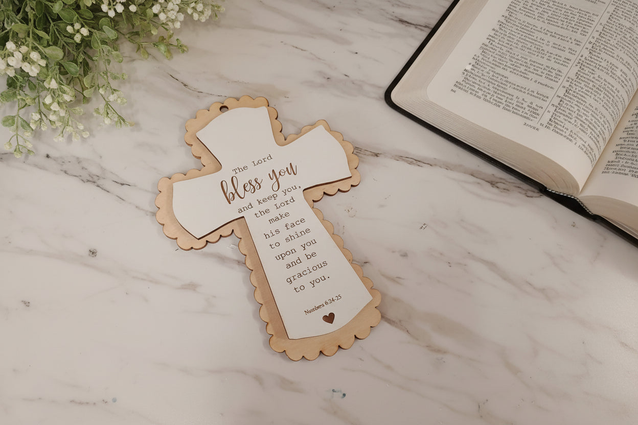 Decorative cross with text on a marble surface next to an open book