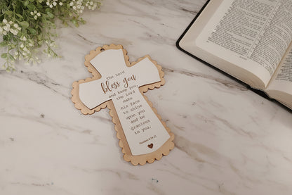 Decorative cross with text on a marble surface next to an open book